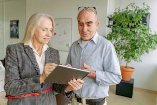 Two older businesspeople looking at a tablet screen